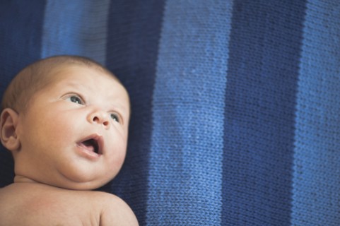 Close up of newborn mixed race baby laying on striped blanket
