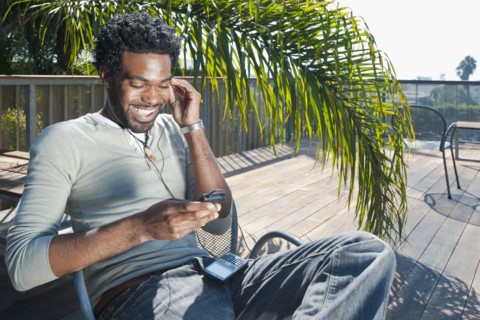 Black man listening to mp3 player on patio