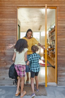 Black mother greeting daughters at front door