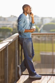 Black man talking on cell phone on balcony