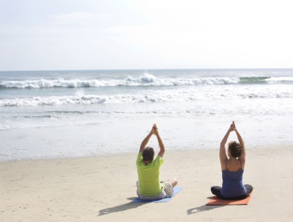 Caucasian couple meditating on beach