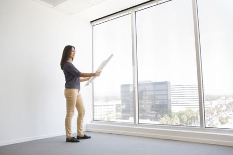 Woman reading blueprints in empty office