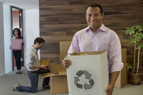 Hispanic businessman carrying cardboard box in office
