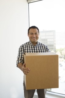 Hispanic businessman carrying cardboard box in office