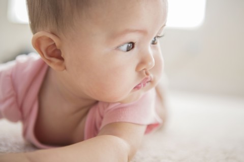 Mixed race baby girl laying on carpet