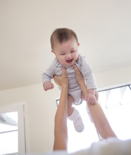 Mother holding baby girl overhead