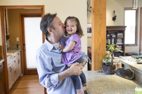 Father kissing daughter in kitchen