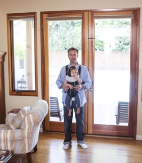 Father holding daughter in sling in living room
