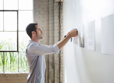 Caucasian architect hanging photos in office