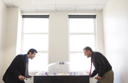 Businessmen playing foosball together in office