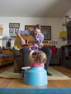 Caucasian father playing guitar for daughter