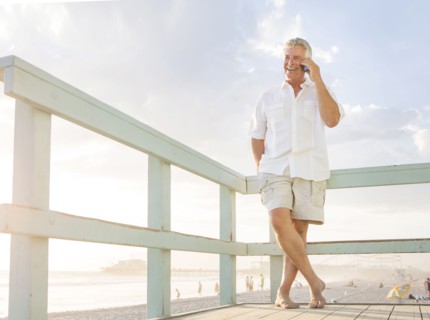 Caucasian man talking on cell phone on boardwalk at beach