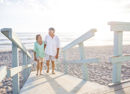 Caucasian couple walking on wooden boardwalk on beach