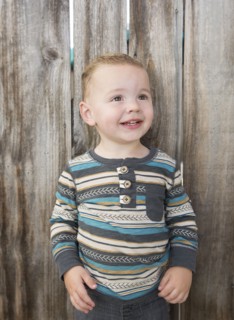 Caucasian boy smiling near wooden fence