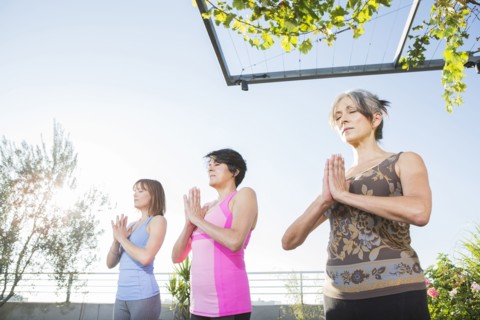 Women practicing yoga together on urban rooftop