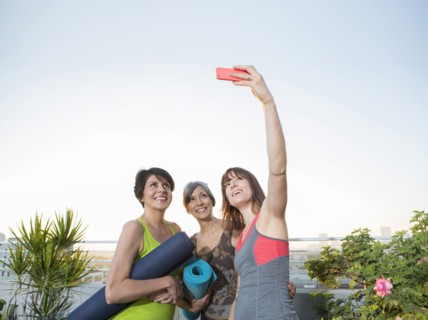 Women taking cell phone selfie on urban rooftop