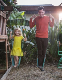 Caucasian father and daughter standing on swings