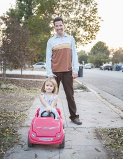 Caucasian father pushing daughter in toy car