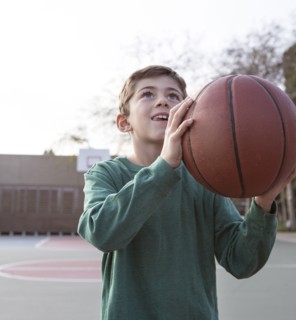Caucasian boy holding basketball on court