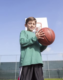 Low angle view of Caucasian boy holding basketball on court