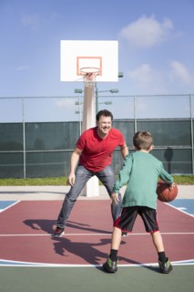 Caucasian father and son playing on basketball court