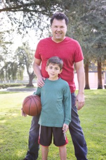 Caucasian father and son smiling in park with basketball