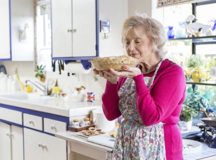 Older Caucasian woman baking pie in kitchen