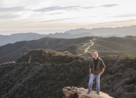 Older Caucasian man standing on rocky hilltop