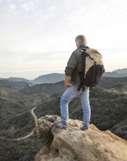 Older Caucasian man standing on rocky hilltop