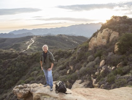 Older Caucasian man standing on rocky hilltop
