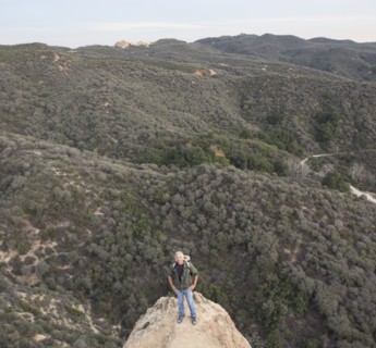 High angle view of older Caucasian man standing on rocky hilltop