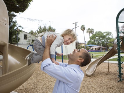 Hispanic father and son playing on playground