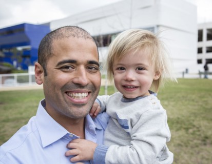 Hispanic father and son smiling in field