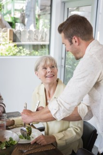 Caucasian man serving mother at table