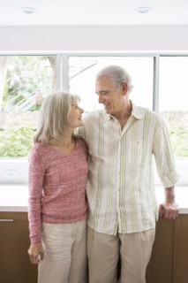 Older Caucasian couple hugging in kitchen