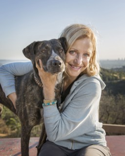 Caucasian woman hugging dog on hilltop