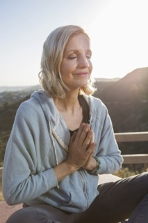 Caucasian woman meditating on hilltop