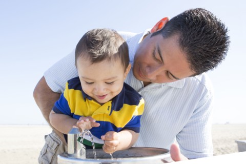 Hispanic father and son playing with water fountain