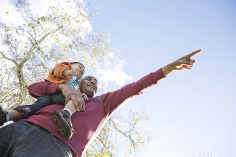 Low angle view of Hispanic father and son pointing outdoors