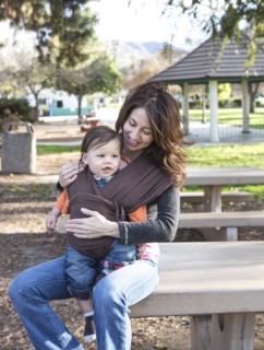 Hispanic mother wearing son in carrier in park