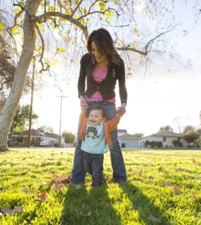 Hispanic mother playing with son in park