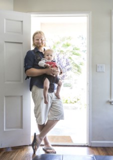 Caucasian father wearing son in harness in doorway