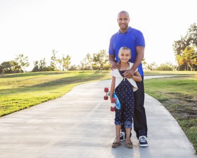 Father and daughter hugging with skateboard in park