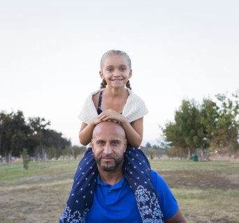 Father carrying daughter on shoulders in park
