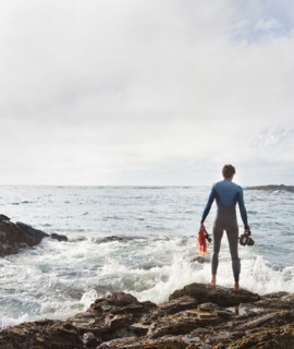 Hispanic diver wearing wetsuit on beach