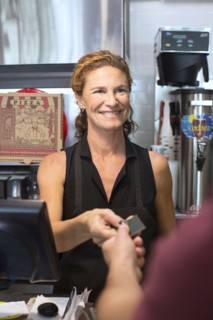 Server helping customer purchase pizza in cafe