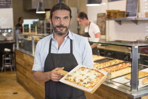 Server holding pizza in cafe