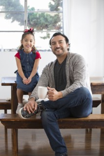 Hispanic father and daughter smiling at table