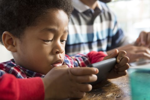 Mixed race boy using cell phone at table