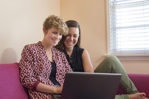 Caucasian lesbian couple using laptop on sofa